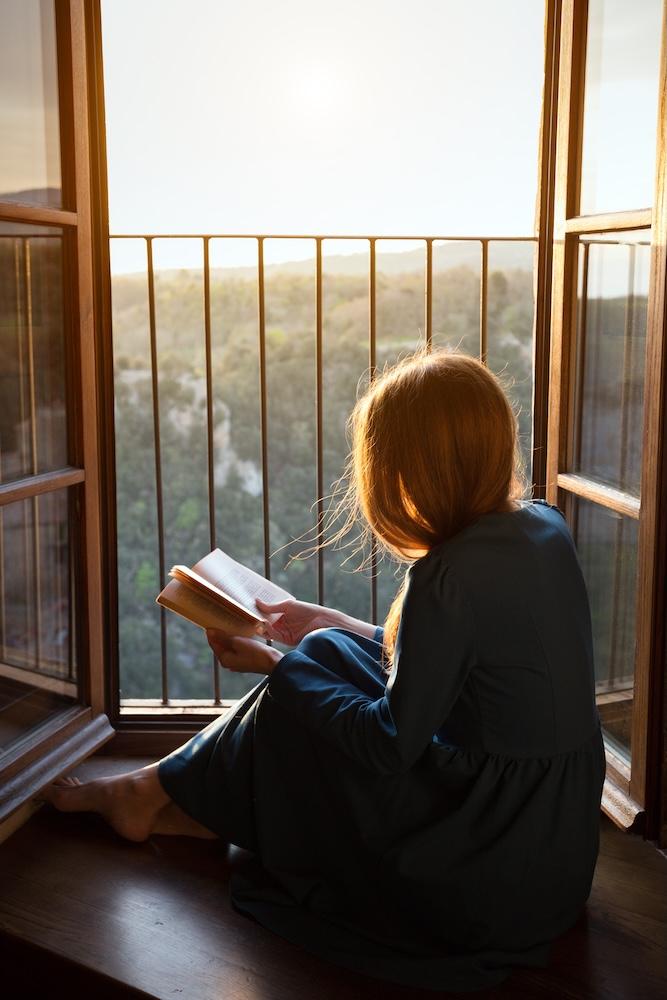 Woman reading a book by her balcony