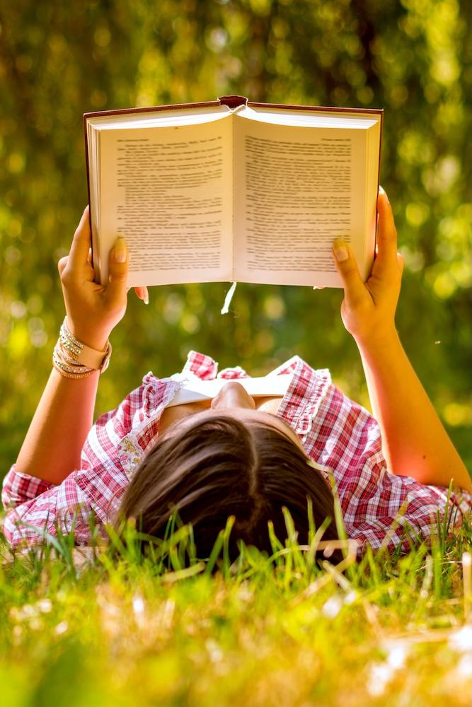 Woman lying in the grass reading a book