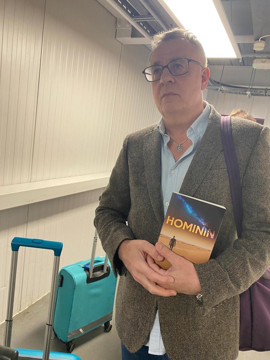 Person holding the book Hominin by Neil R McAdam