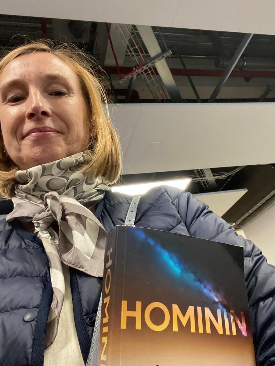 Person holding the book Hominin by Neil R McAdam