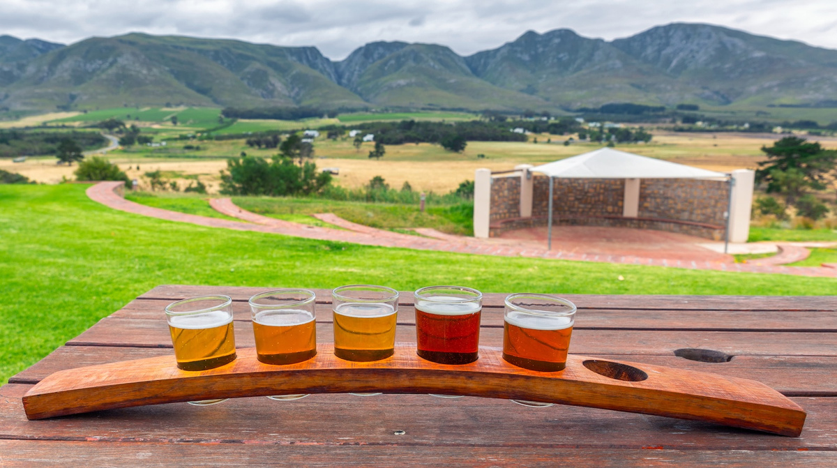 Beer tasting glasses on a wooden tray outside the brewery with a beautiful view of the mountains in South Africa