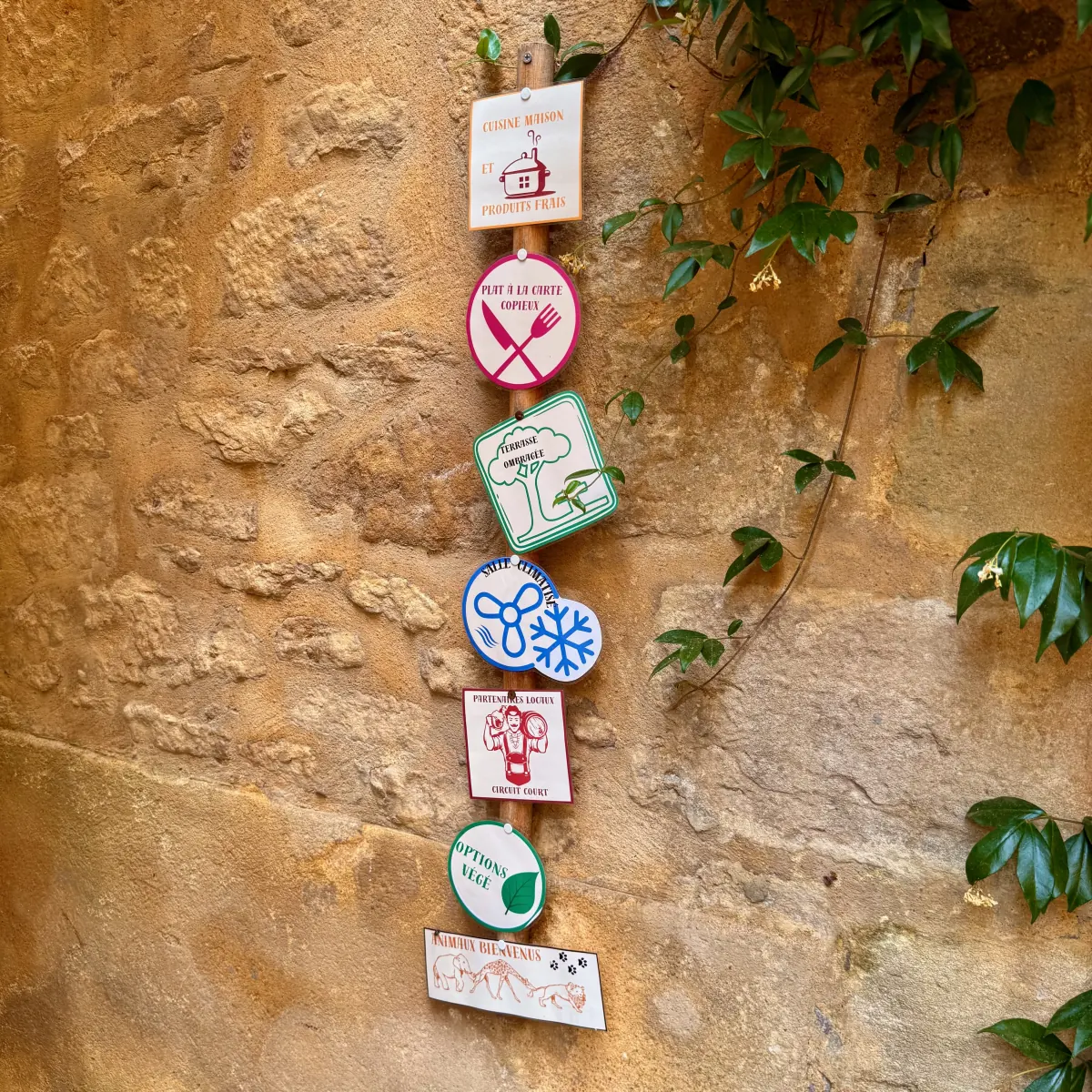 Hand-painted signs hanging on a stone wall outside a restaurant