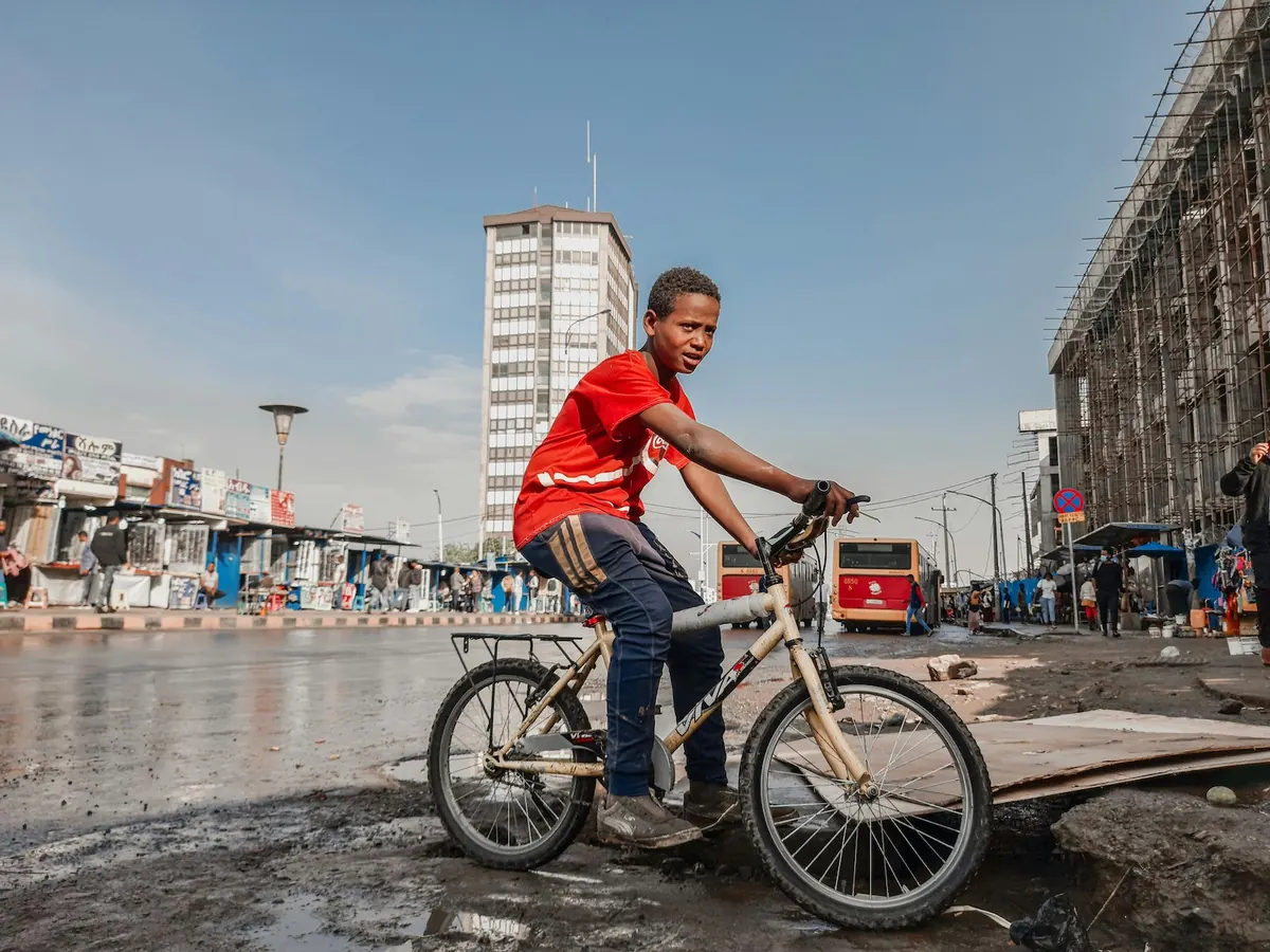 A young person on a bicycle in an African city