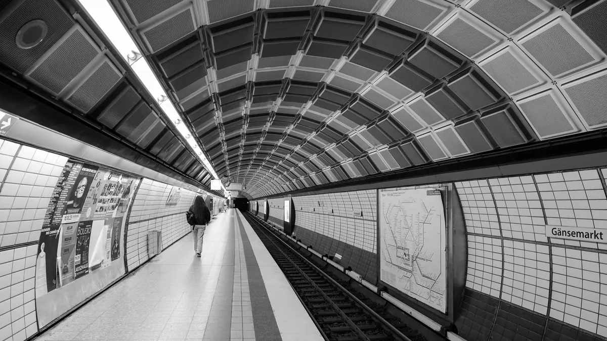 Black-and-white view along an underground station platform beneath a patterned ceiling