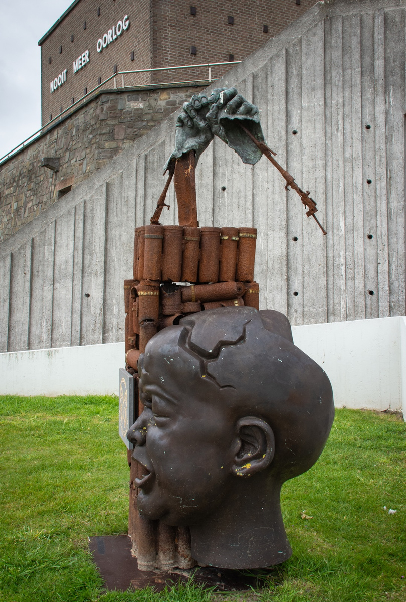 <p>Nooit meer Oorlog (No more war) in Flemish on the side of the UN Peace Museum at Diksmuide and one of the sculptures in the garden below that has been created using remnants of the deadly equipment of war</p>