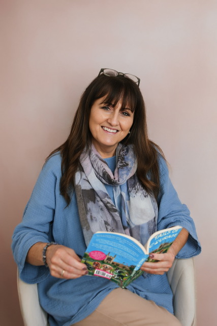 Doreen Connor smiling and holding a copy of Tails of Courage