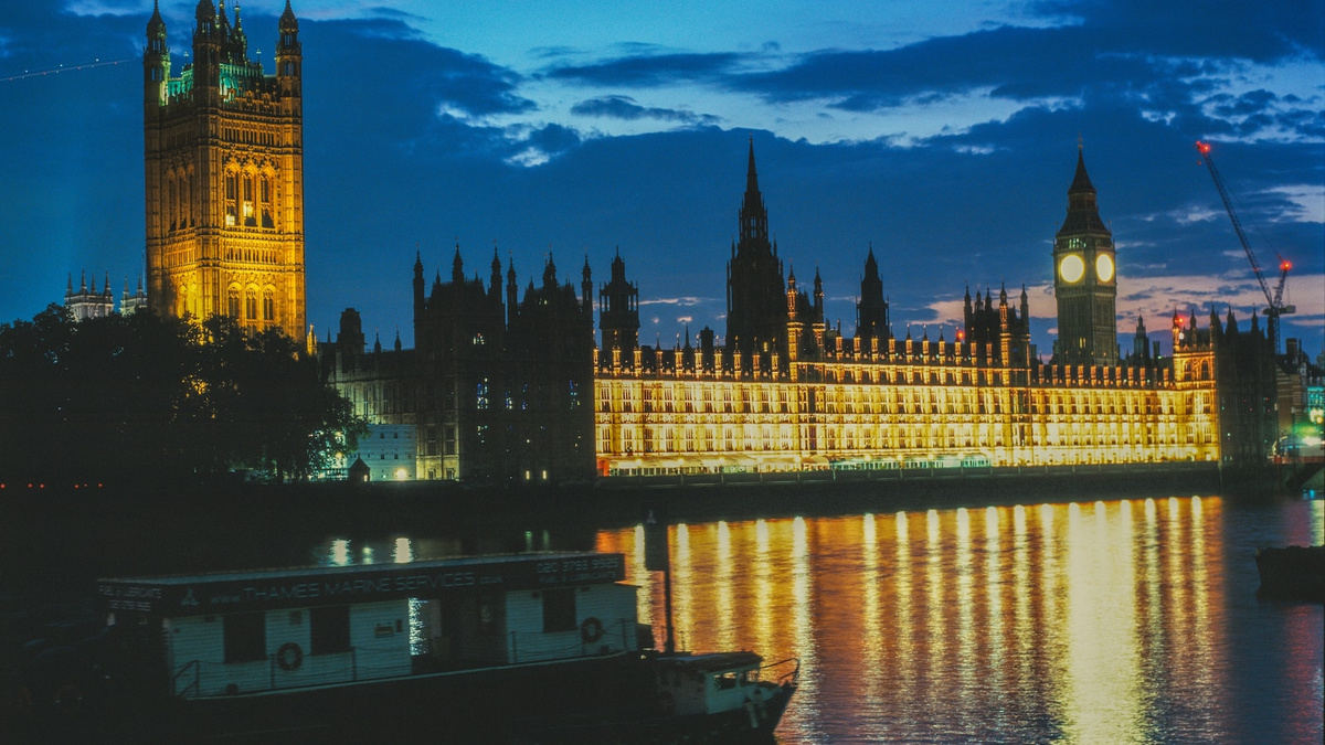 The Palace of Westminster illuminated at dusk beside the River Thames