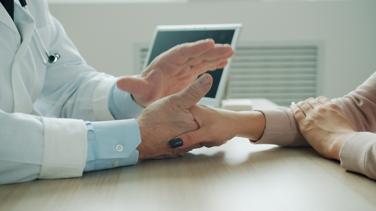 A doctor offering reassurance by holding a patient’s hand during a consultation