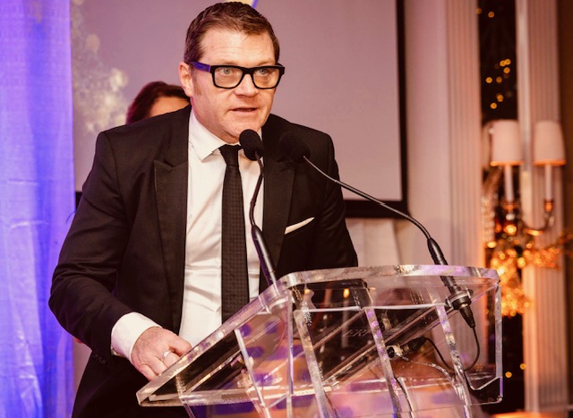 Tom Hadley speaking from a lectern at an evening event