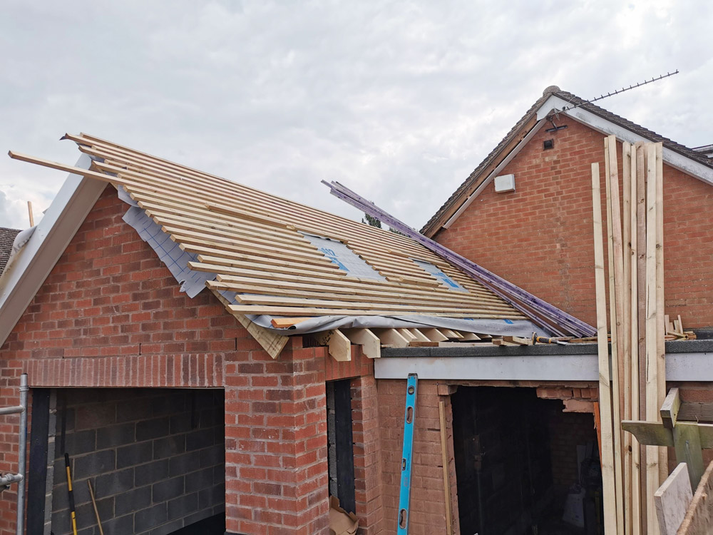 New roof timbers and battens on a red brick garage extension