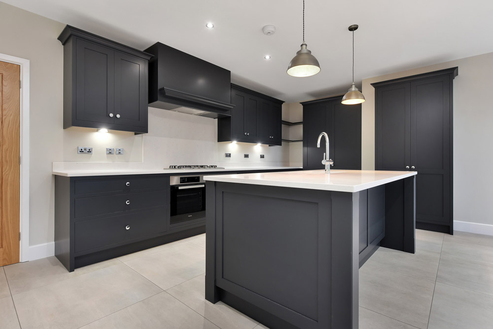Fitted kitchen with dark grey shaker-style units, a central island and pendant lights