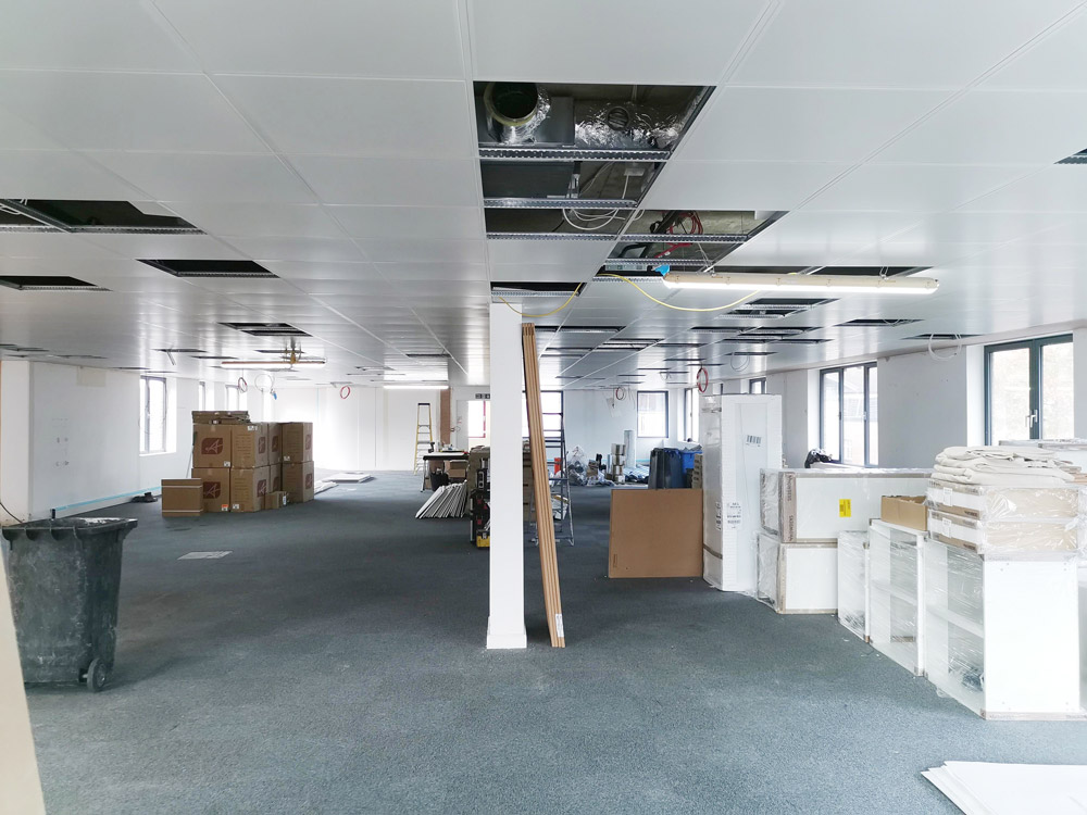 Open-plan office being refitted with a suspended ceiling and boxes of materials