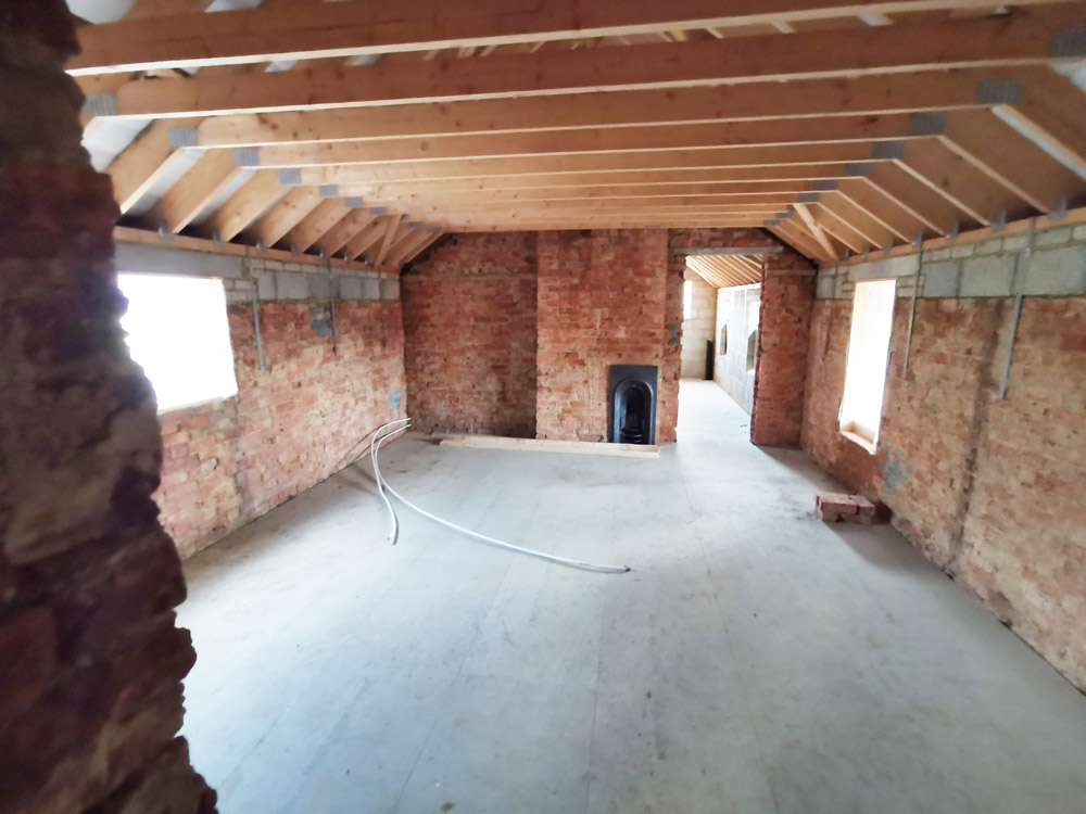 Stripped-back interior of a brick building conversion with new roof timbers