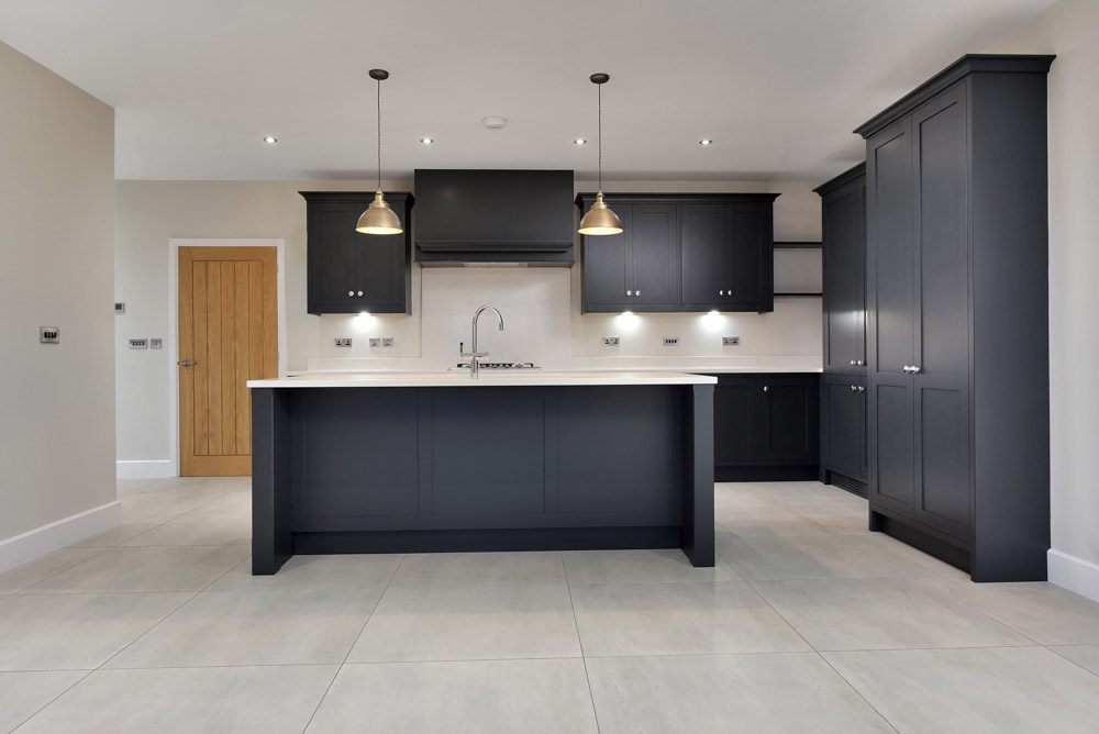 Kitchen with dark shaker-style cabinets, a white-topped island and pendant lights