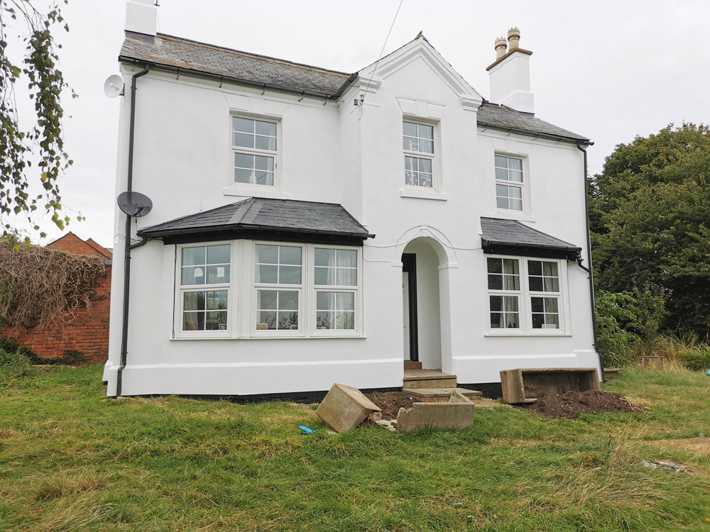 White rendered detached period house with bay windows after renovation