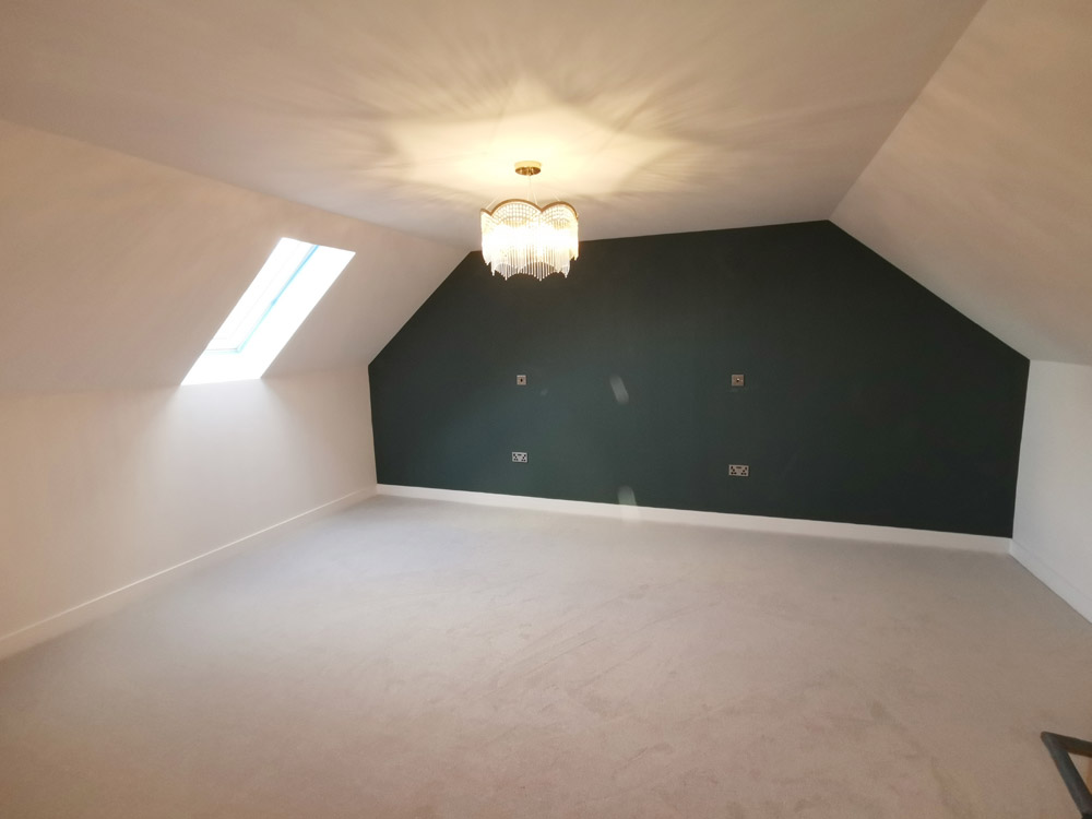 Loft conversion bedroom with a roof window, dark feature wall and pendant light