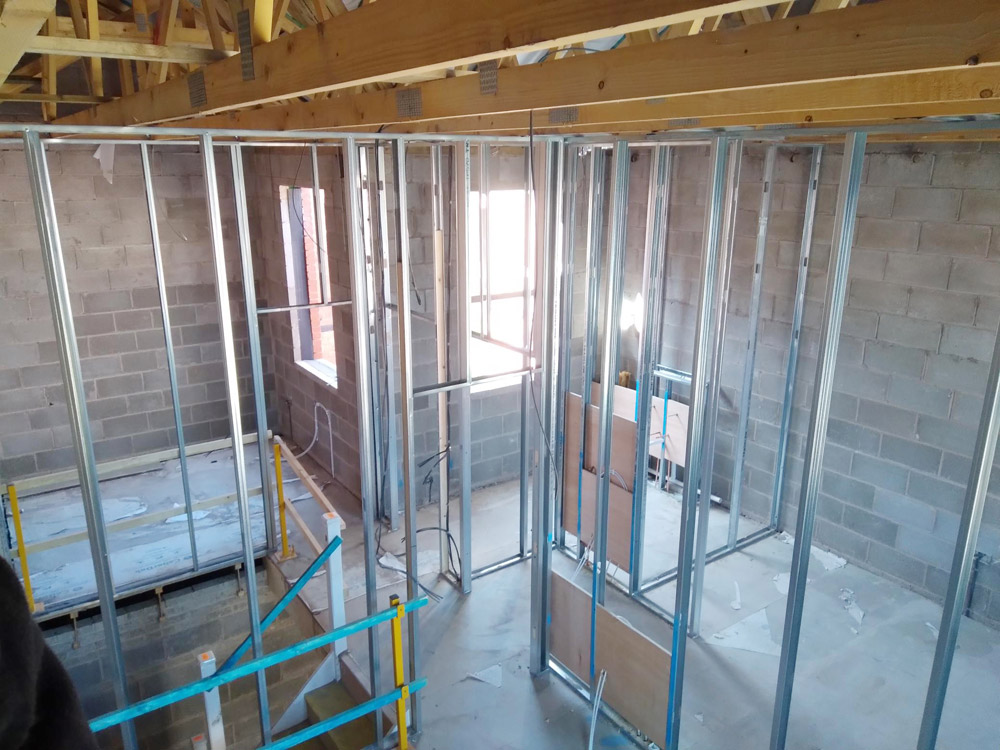 Metal stud partition framing in a building conversion beneath exposed roof trusses