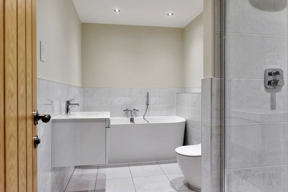 Bathroom with a bath, wall-hung toilet and white tiling