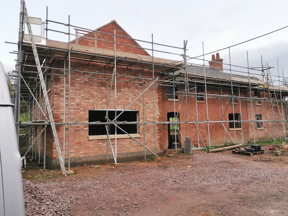 Scaffolding along a long red brick building during renovation