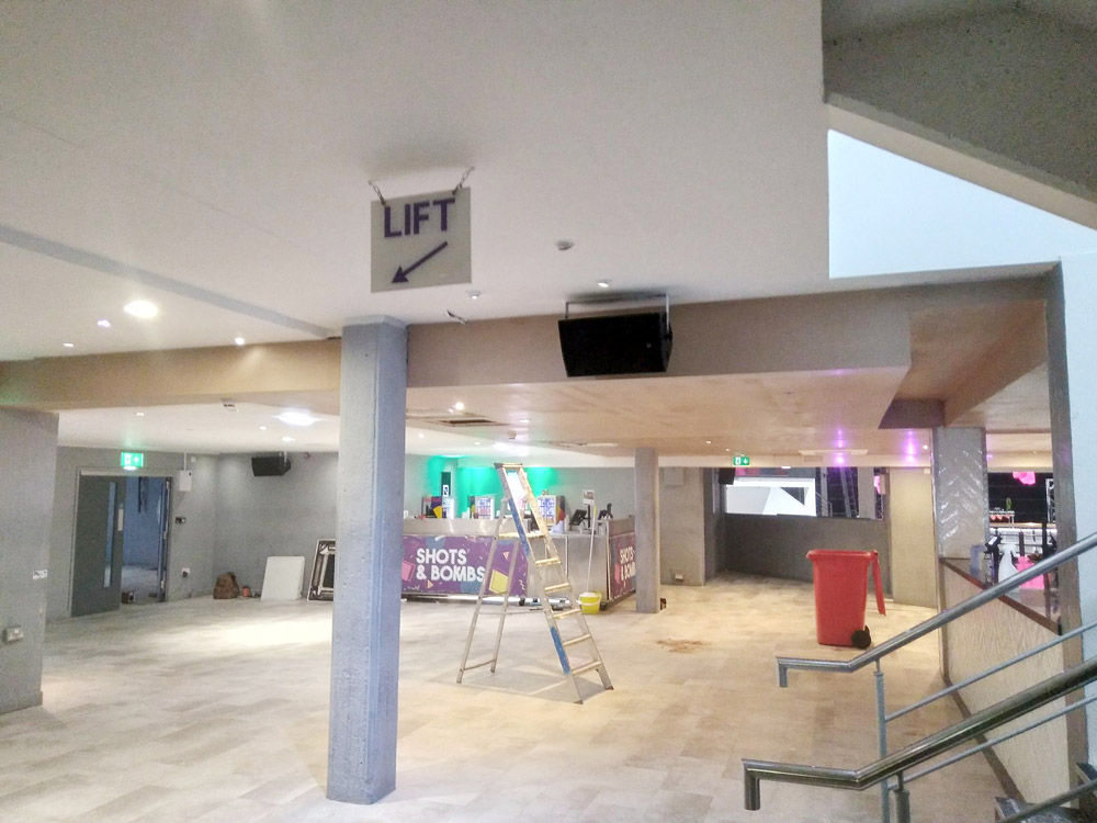 Commercial interior refurbishment in progress with an exposed steel column, lift sign and stepladder