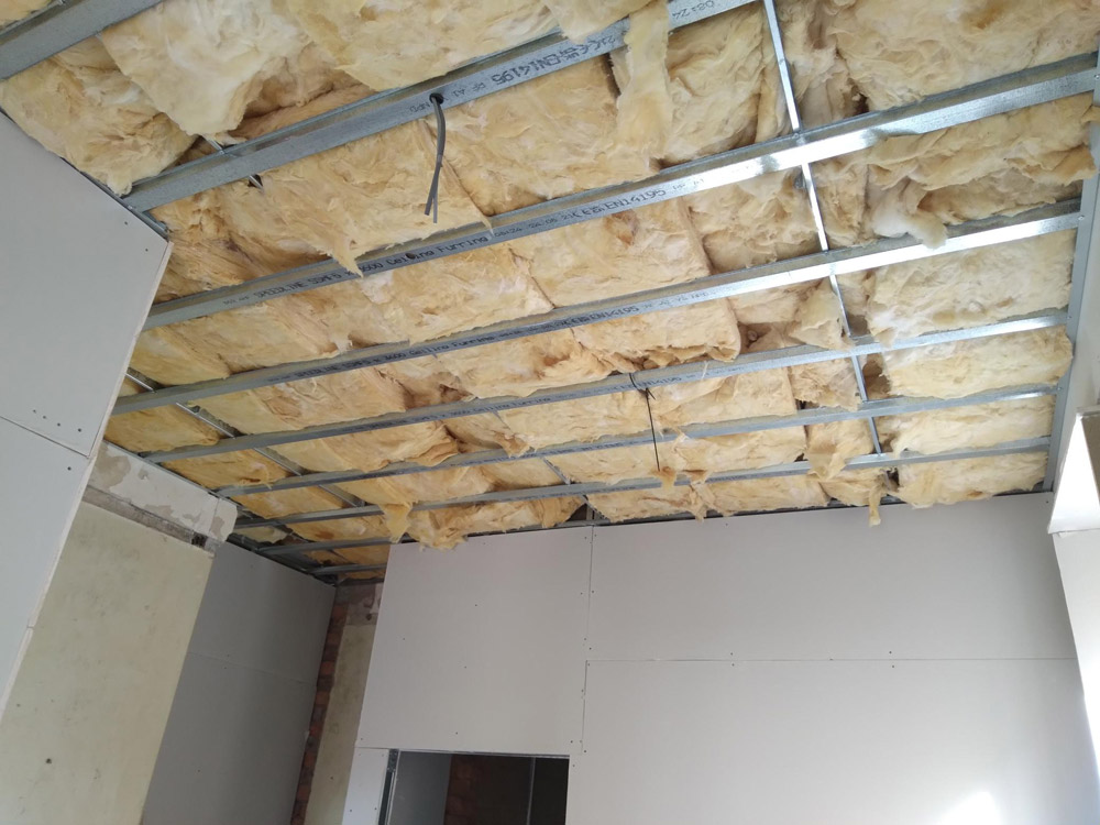 Metal ceiling framework and mineral wool insulation in a room under renovation
