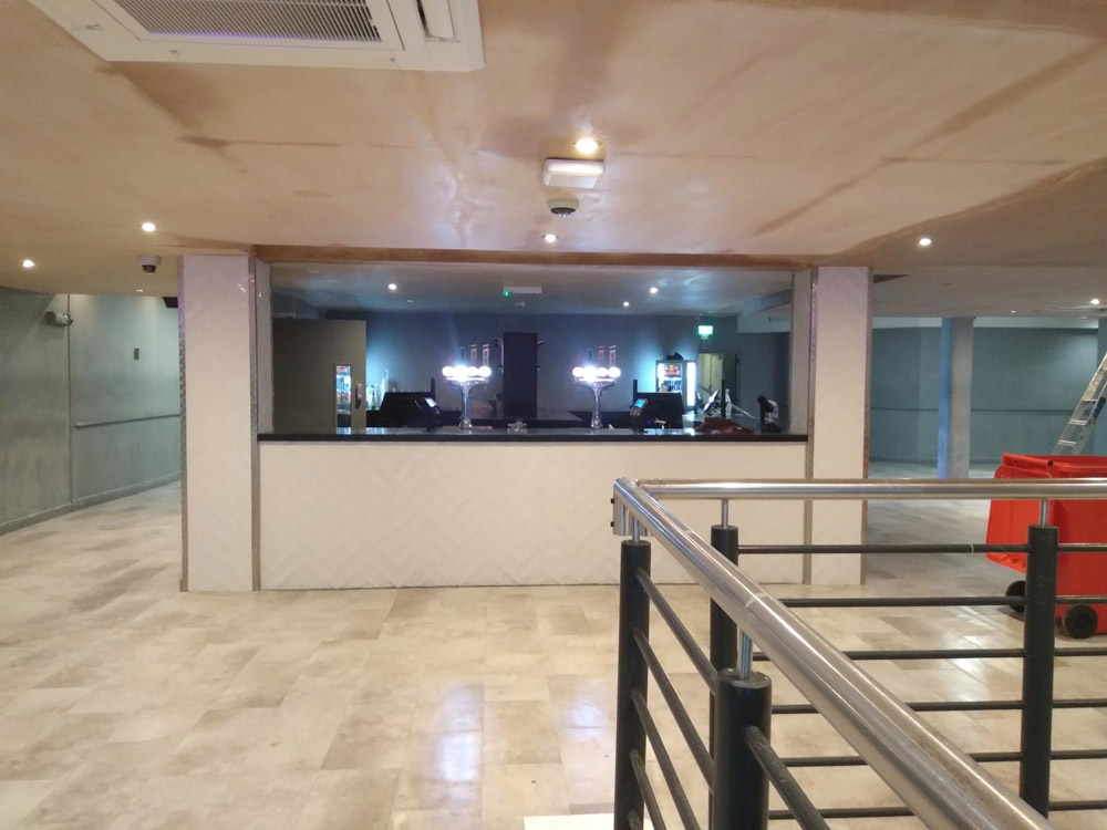 Refurbished commercial interior with a marble-effect floor, bar counter and metal balustrade