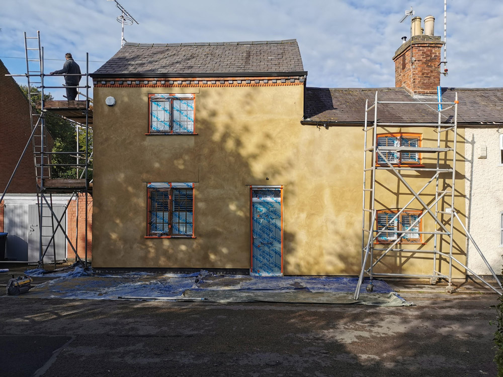 Rendered two-storey house with scaffolding during an exterior renovation
