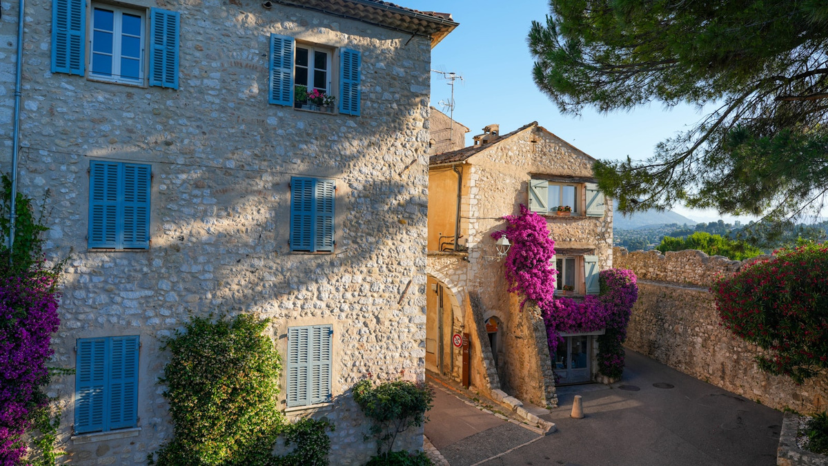 Stone houses with blue shutters and pink bougainvillea in a village in the south of France
