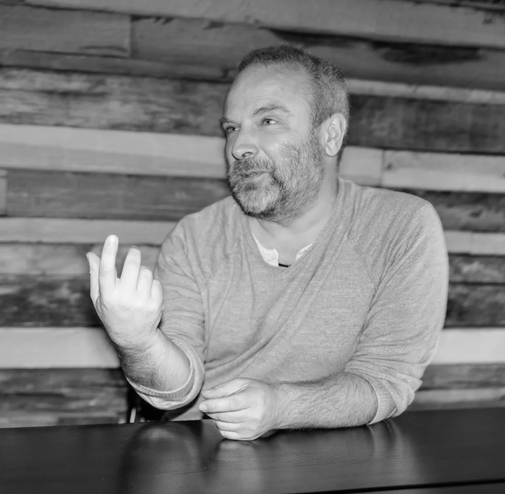 Matt Potter seated at a table, gesturing as he talks.