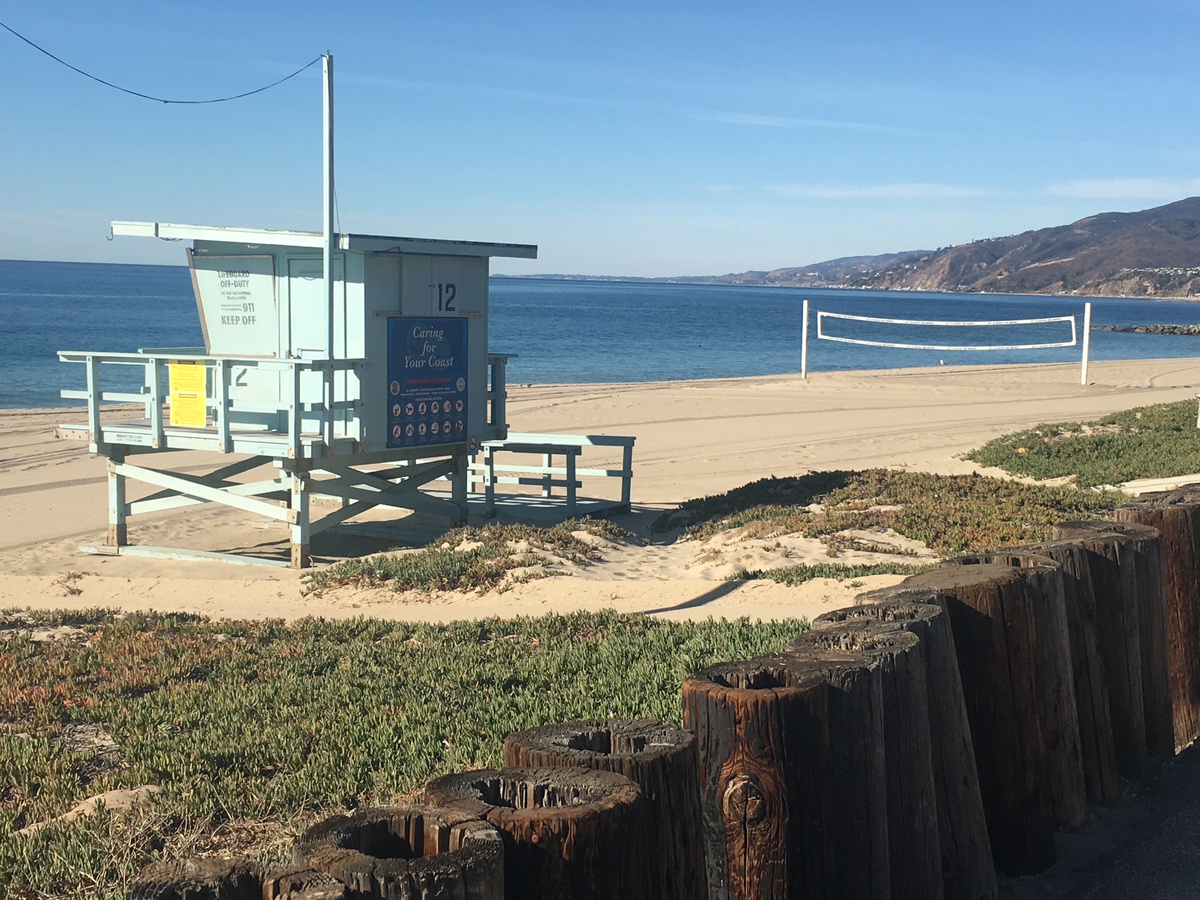 A pale blue lifeguard tower and volleyball net on the beach