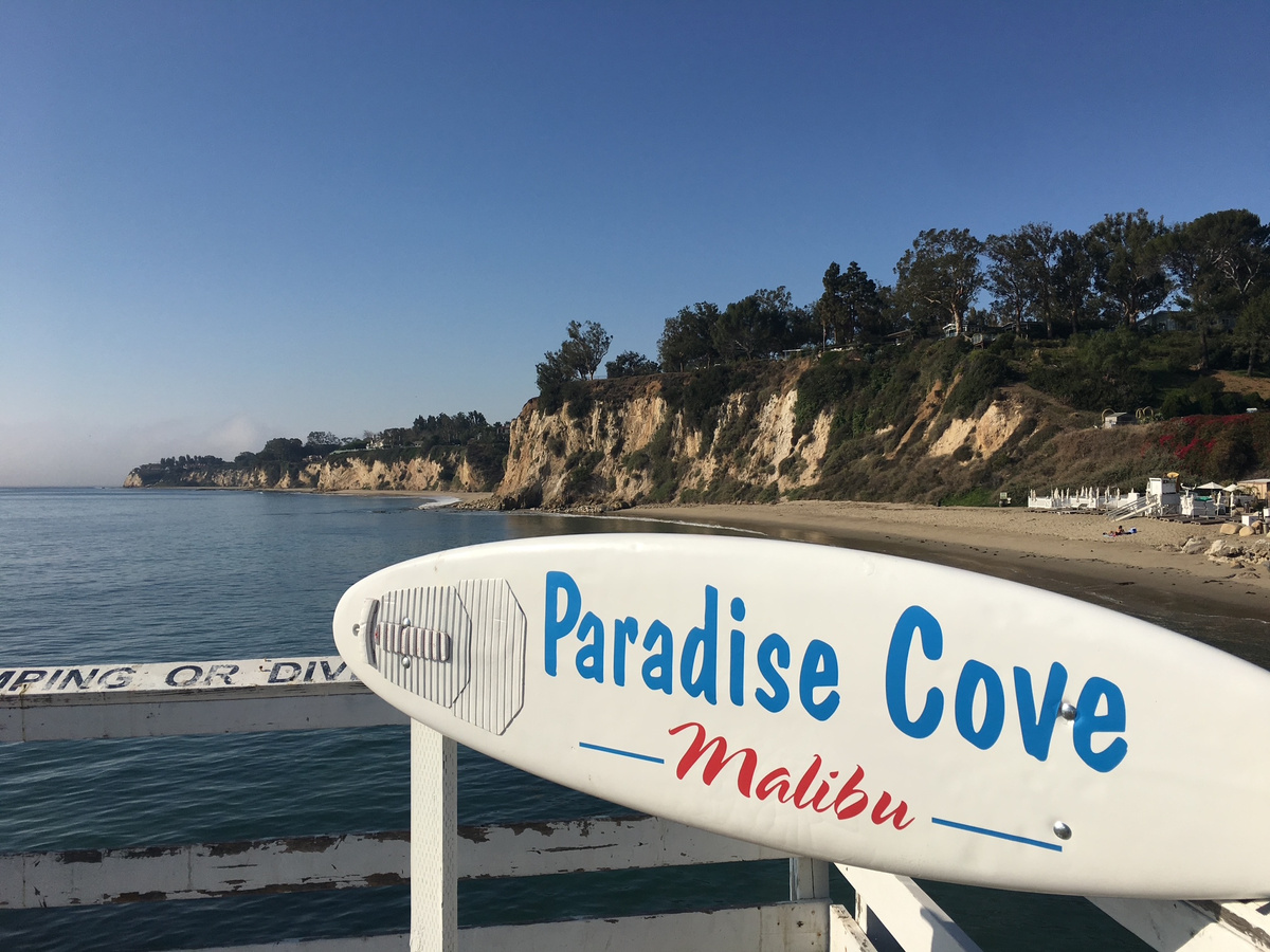 A Paradise Cove Malibu surfboard sign beside the beach