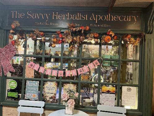 The window of The Savvy Herbalist Apothecary, decorated with autumn garlands and filled with books and jars