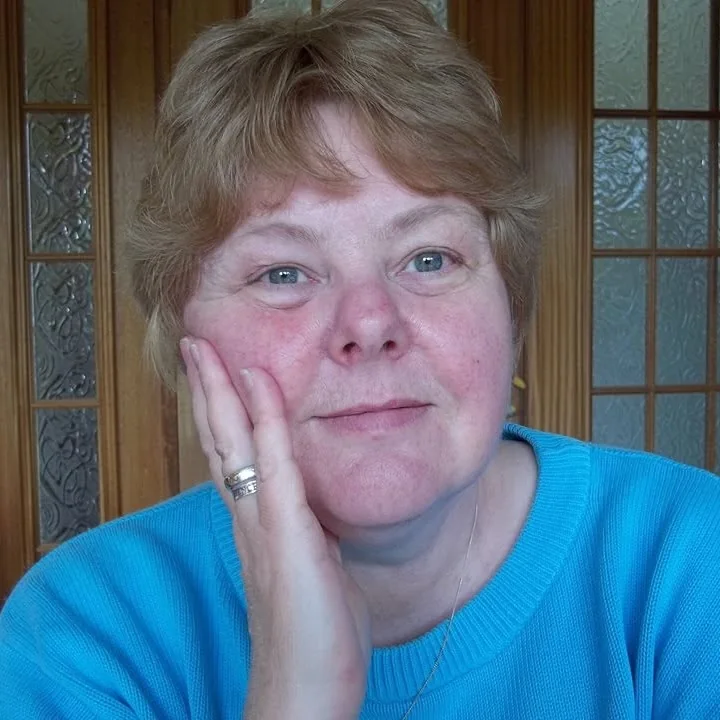 Susan St Clare resting her chin on her hand, wearing a turquoise jumper