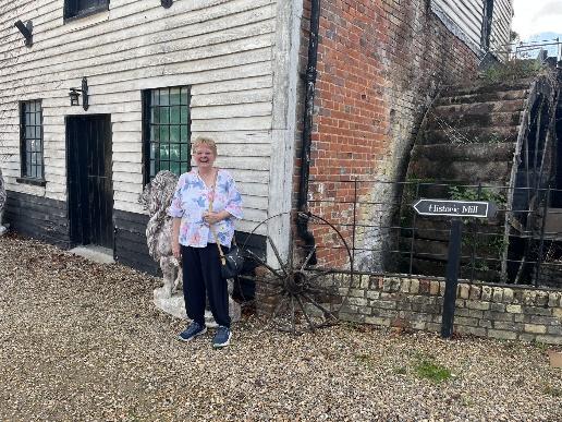 Outside the Old Watermill in Barton, beside the water wheel and a Historic Mill sign