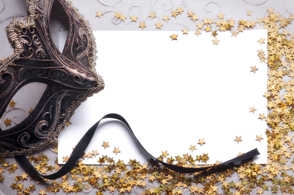 An ornate masquerade mask, gold stars and a blank card